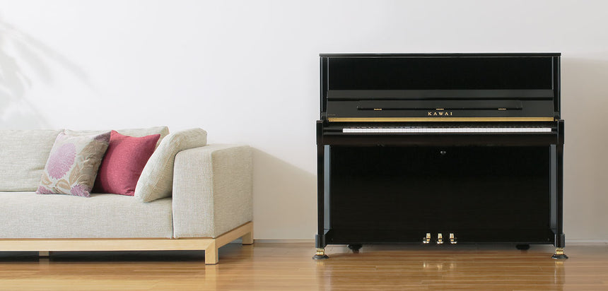 Kawai K-300, schwarz poliert – Frontansicht neben einem Sofa.