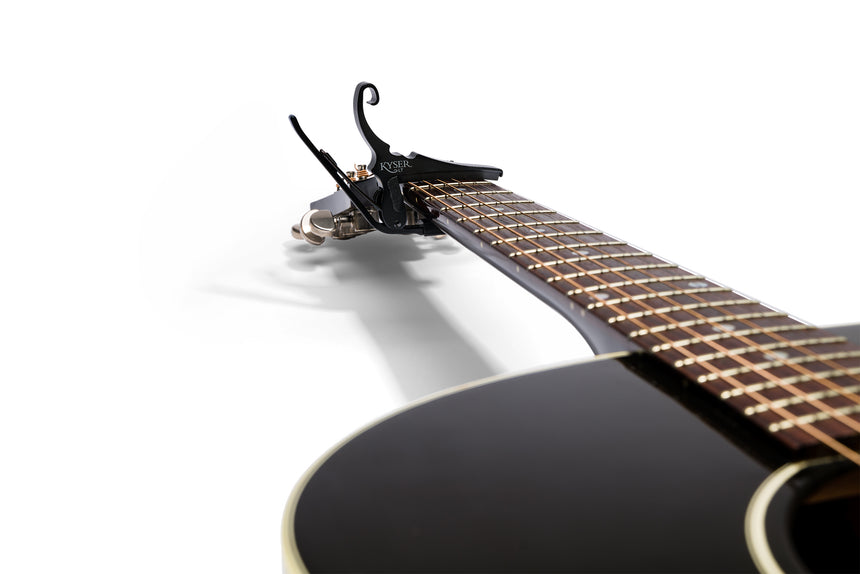 Black Kyser KG6LTA low-tension acoustic guitar capo – attached to an acoustic guitar neck.